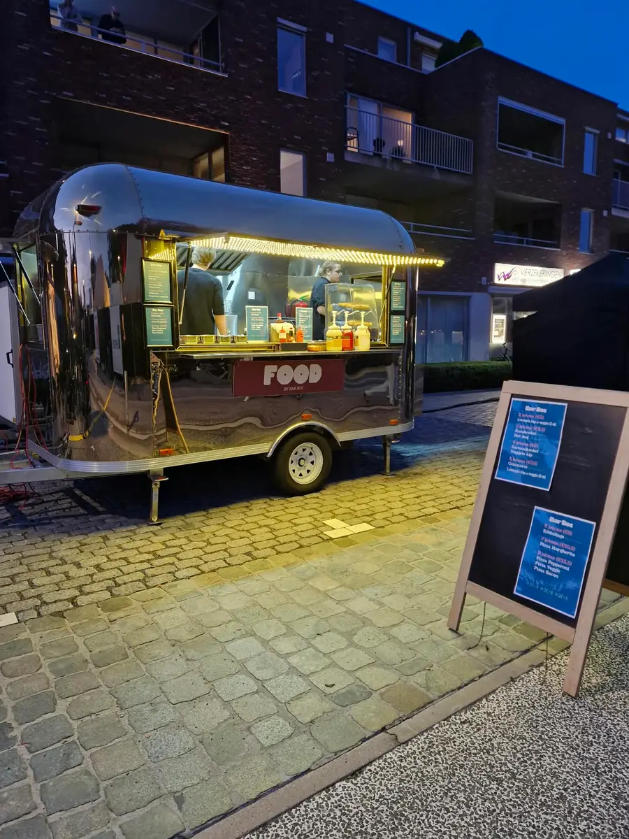Golden Airstream food truck at dusk, warmly lit, with a chalkboard menu next to it
