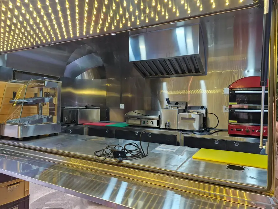 Inside the Airstream kitchen with a stainless steel counter, oven and a ceiling full of lights