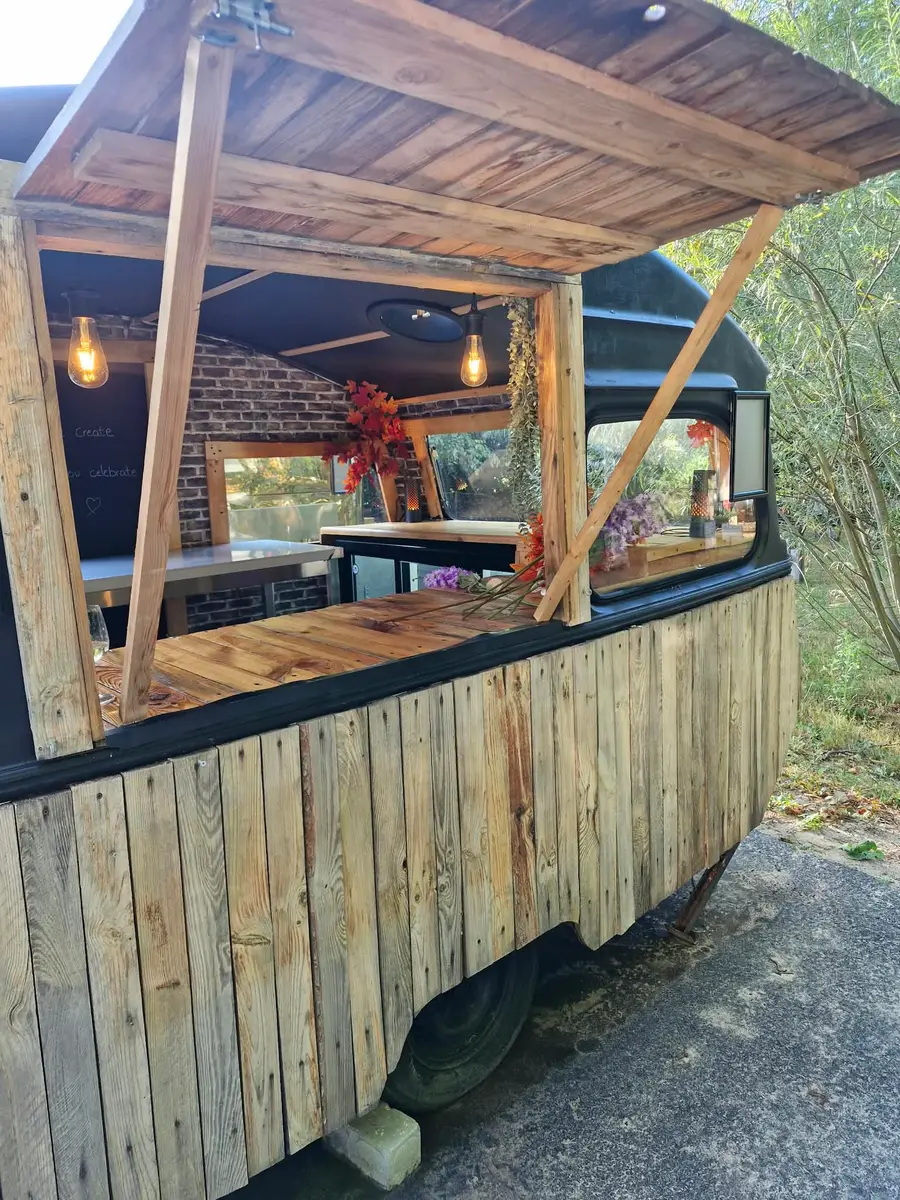 The wooden caravan bar up close in daylight, with a lift-up hatch and warm wooden planks