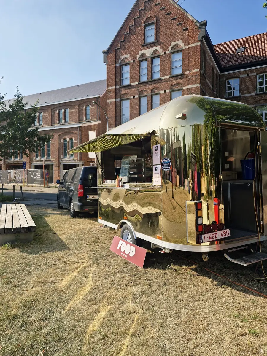 Golden Airstream food truck parked in front of a large brick building