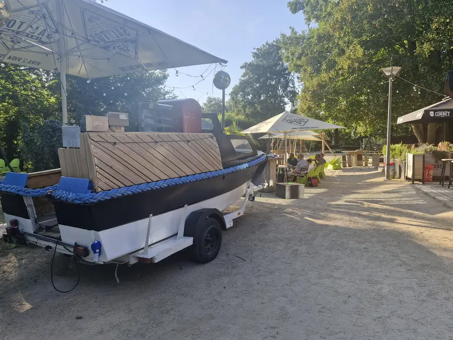 Side view of the boat bar on a sand terrace with parasols and trees