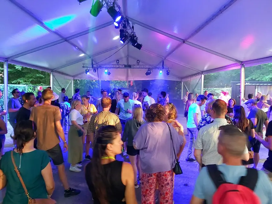 Partygoers dancing in a party tent with purple and blue light