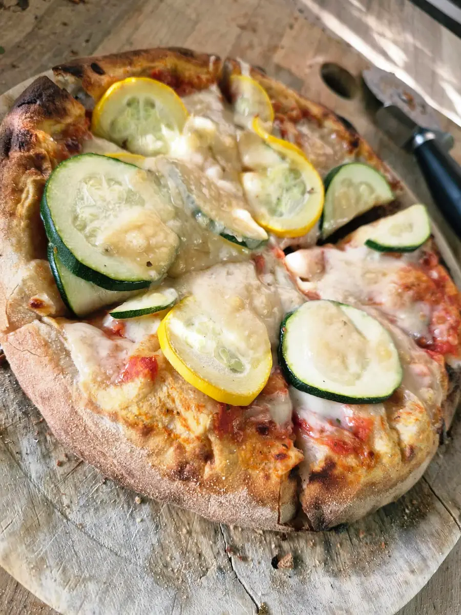 Fresh pizza with courgette and cheese on a wooden board